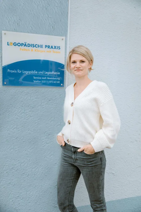 Lena Felten, Inhaberin der Praxis, steht lächelnd neben dem Praxisschild „Logopädische Praxis Felten & Klages mit Team“